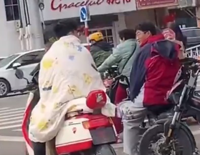 山东突然降温 小伙披棉被骑车
